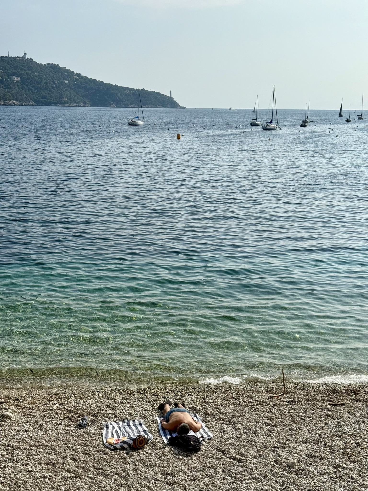 En solande man på en strand vid ett azurblått hav