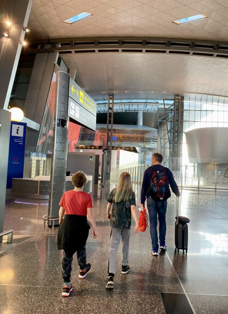 Två barn och en man går på en flygplatsen i Doha